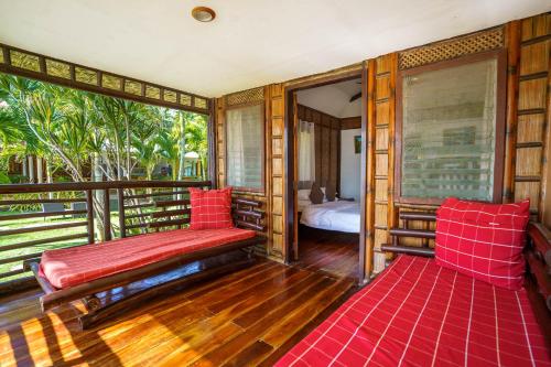a room with a balcony with a bed and red pillows at Charisma Beach Resort in Siquijor