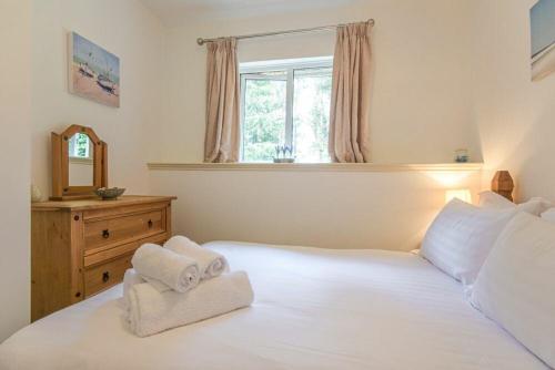 a bedroom with a white bed with towels on it at Middlemoor Cottage in Alnwick