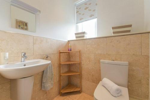 een badkamer met een wastafel, een toilet en een raam bij Middlemoor Cottage in Alnwick