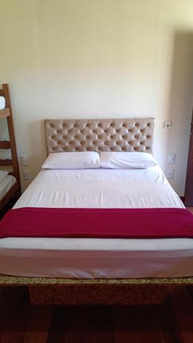a bedroom with a large bed with white sheets and red blanket at Pousada Adventures - Suites Luxo Hidromassagem - Piscina - Capitolio MG in Capitólio