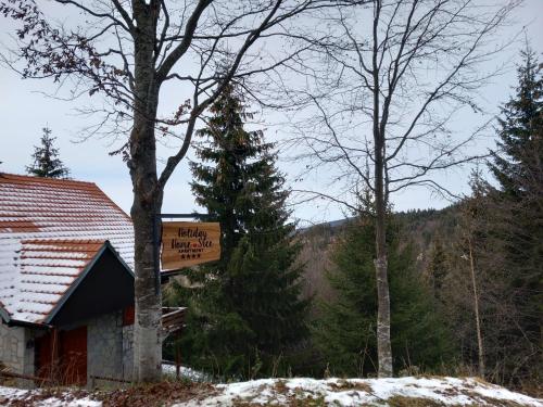 a sign for a lodge with a tree in the background at Apartments Holiday Home Srce in Kopaonik