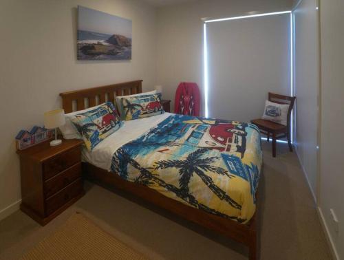 a bedroom with a bed with palm trees on it at Modern air-conditioned 3-bedroom townhouse in centre of Cape Woolamai in Cape Woolamai