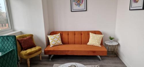 Flitwick Luxury Apartment - Sleeps 4 في فليتويك: كنب برتقالي وكرسي في الغرفة