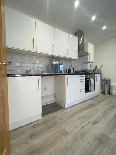 cocina con armarios blancos y suelo de madera en Flitwick Luxury Apartment - Sleeps 4, en Flitwick