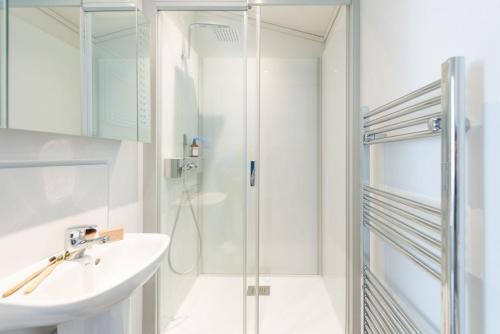 a white bathroom with a sink and a shower at Bluebell Lodge, 29 Roadford Lake Lodges in Lifton