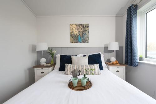 a bedroom with a large white bed with blue curtains at Bluebell Lodge, 29 Roadford Lake Lodges in Lifton