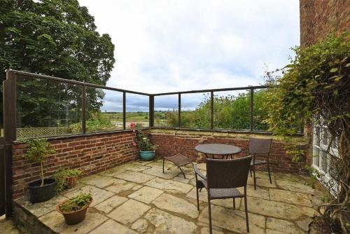 a patio with a table and chairs on a brick wall at The Old Watchtower in Alnmouth