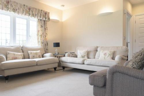 a living room with two white couches and a window at Keeper's View in Bamburgh