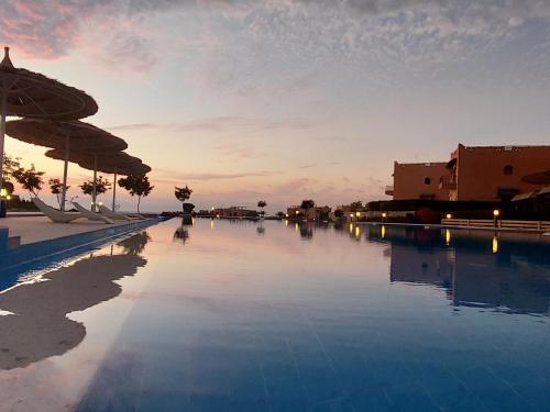 une grande piscine avec un coucher de soleil en arrière-plan dans l'établissement La Hacienda - Ras Sedr Chalet - Ras Sudr, à Ras Sudr