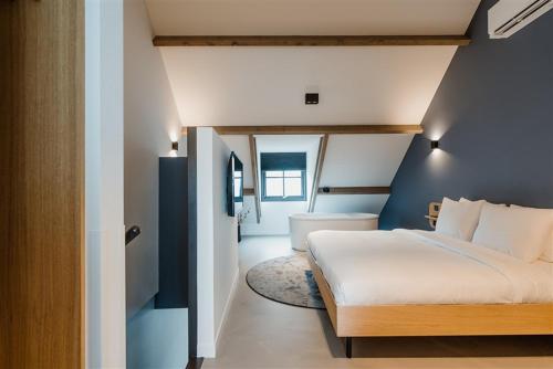 een slaapkamer met een wit bed en een blauwe muur bij Hotel Katoen in Goes