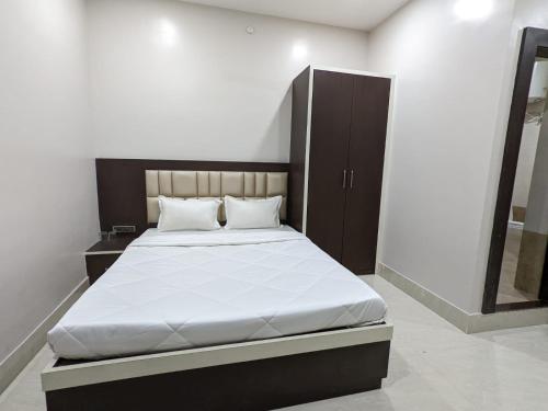 a bedroom with a bed with a black headboard and a mirror at The Golden Sand in Jamshedpur