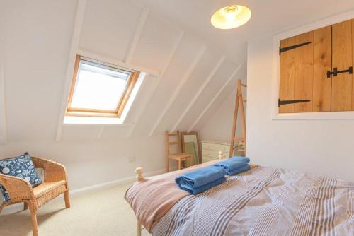 a bedroom with a bed and a window and a chair at Partan Cottage in Burnmouth