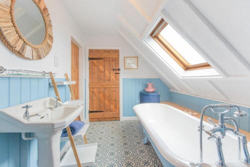a bathroom with a white tub and a sink at Seal Cottage in Burnmouth