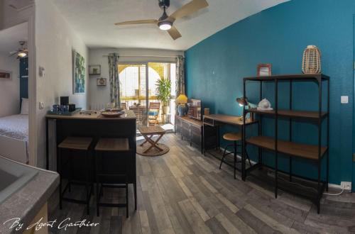 een woonkamer met blauwe muren en een keuken met een tafel bij Charmant 2 pièces les pieds dans l'eau in Sète