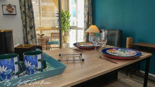 - une table en bois avec 2 assiettes et des verres à vin dans l'établissement Charmant 2 pièces les pieds dans l'eau, à Sète
