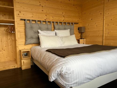 a bedroom with a large bed with wooden walls at Hôtel L'Atelier de Donat in Malbuisson