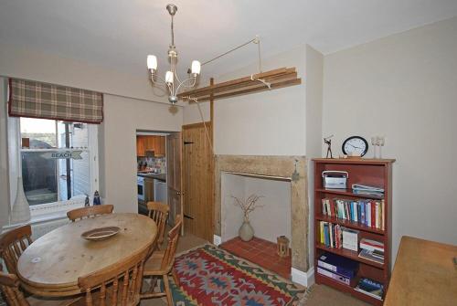a living room with a table and chairs and a fireplace at Beach House Alnmouth in Alnmouth