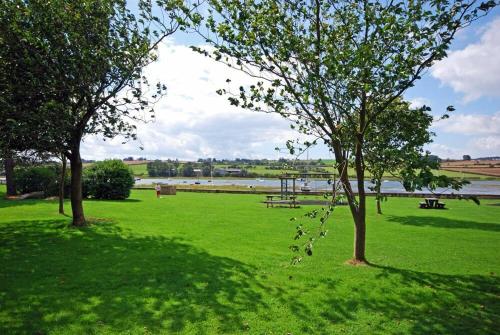 a park with benches and trees in the grass at Beach House Alnmouth in Alnmouth