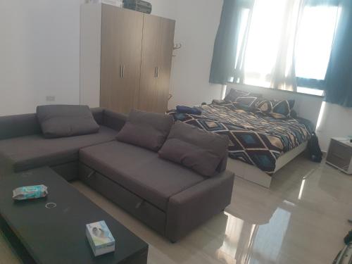 a living room with a couch and a bed at Cheerful 1BR Close to Abu Dhabi Airport and YAS Island in Abu Dhabi