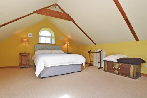 1 dormitorio en el ático con cama y ventana en The Granary, en Newton by the Sea