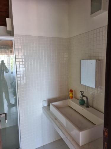 a white bathroom with a sink and a mirror at Casa ferradura com piscina e hidromassagem in Búzios