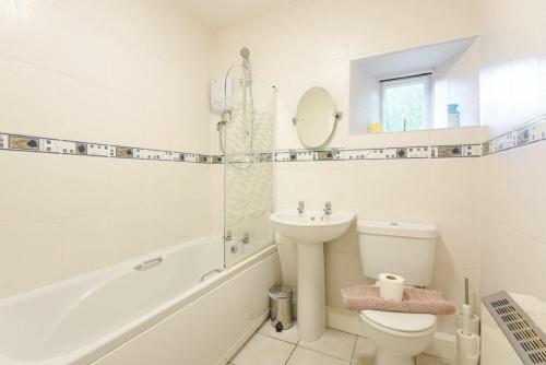 a white bathroom with a toilet and a sink at Dunlin Cottage in Bamburgh
