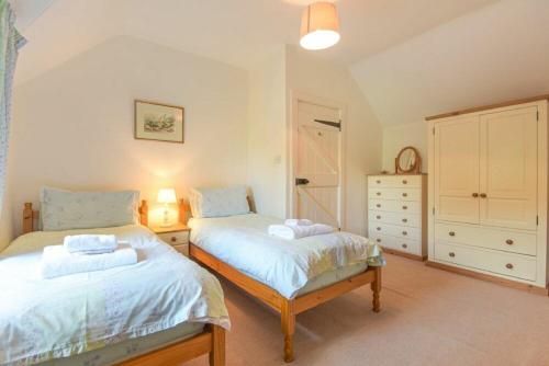a bedroom with two beds and a dresser at Dunlin Cottage in Bamburgh