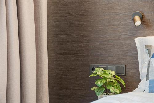 a plant in a vase next to a wall at Aiden by Best Western Herning in Herning