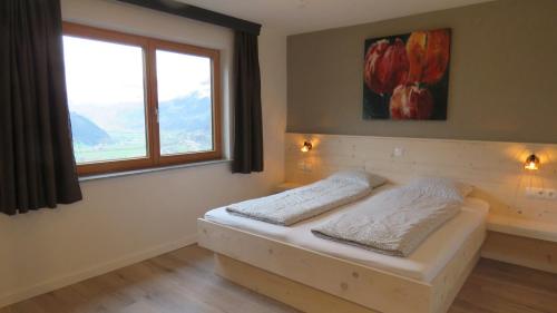 1 dormitorio con 1 cama y ventana en Braunhof Apartments, en Hainzenberg