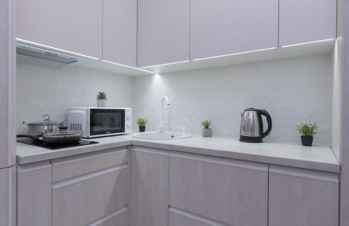 a white kitchen with a microwave and a sink at Люкс на Бориспільській ЖК Олімпік Парк, генератор на будинку in Kyiv