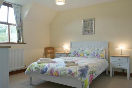 een slaapkamer met een bed, 2 tafels en een raam bij Smithy Court in Craster