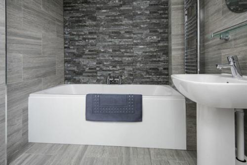 un baño con bañera y lavabo en Smithy Court, en Craster