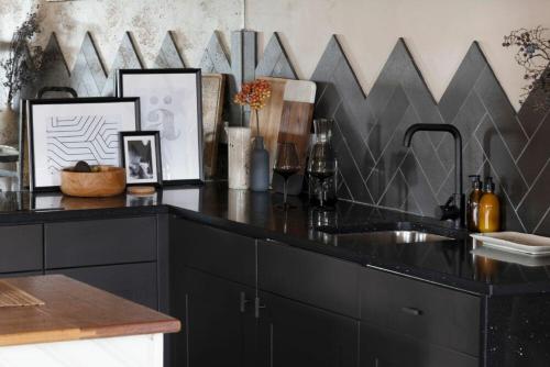 una cocina con encimera negra y fregadero en Lantern View, en Eglingham