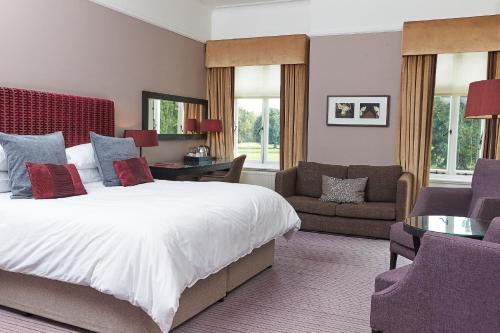 a bedroom with a bed and a couch and a chair at Milton Hill House in Didcot
