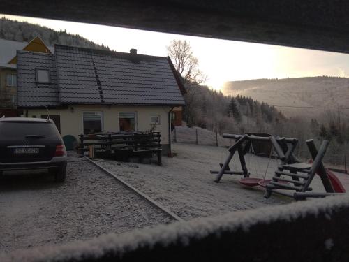 ein Auto, das vor einem Gebäude mit Spielplatz parkt in der Unterkunft Babia Chata in Zawoja