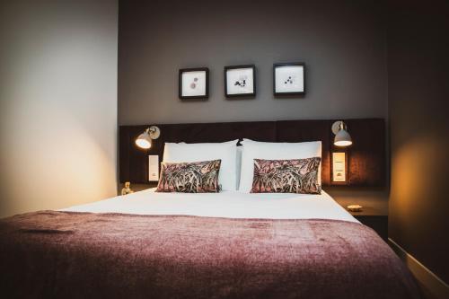 a bedroom with a large bed with three pictures on the wall at Casa de Couros in Guimarães