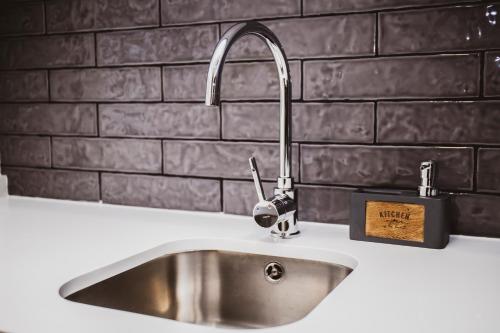 a stainless steel sink in a kitchen with a brick wall at Casa de Couros in Guimarães
