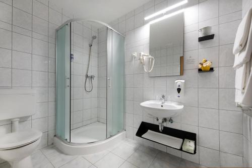 een badkamer met een douche, een toilet en een wastafel bij Zsóry Liget Hotel & Spa Superior in Mezőkövesd