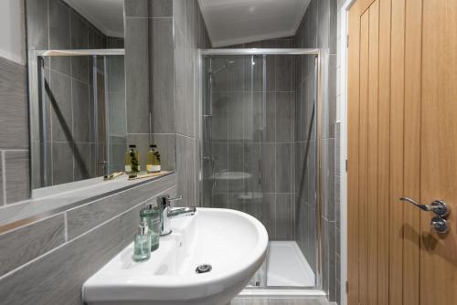 ein Bad mit einem Waschbecken und einer Dusche in der Unterkunft Hawthorne Lodge, 15 Roadford Lake Lodges, Lifton in Lifton