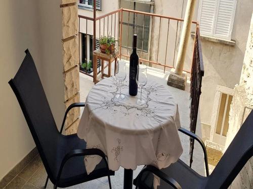 a table with a bottle of wine on a balcony at Studio Joković in Vela Luka