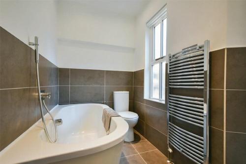 a bathroom with a tub and a toilet and a window at Alnbank in Alnmouth
