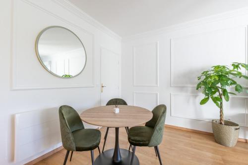 ein Esszimmer mit einem Tisch, Stühlen und einem Spiegel in der Unterkunft La Parisienne by Plaza in Montévrain