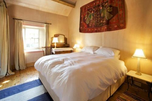 a bedroom with a large white bed and a window at Kirknowe in Jedburgh