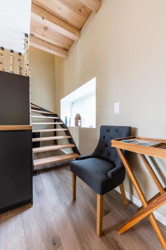 a room with a chair and a table and stairs at La Grange in Birkenwald