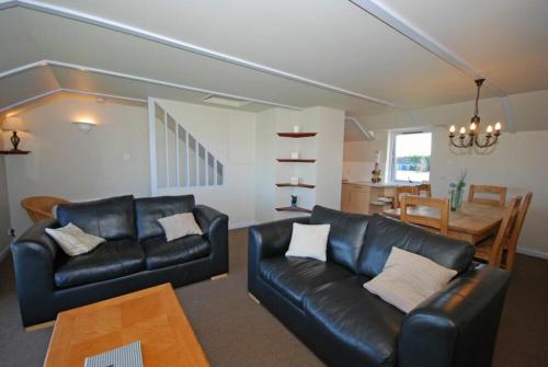 a living room with a black leather couch and a table at Longstone in Embleton