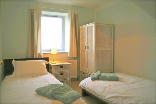 a bedroom with two beds and a desk with a window at Longstone in Embleton