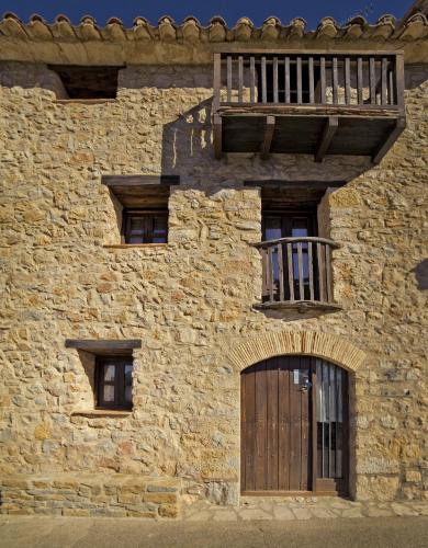 a stone building with a wooden door and a balcony at Casa La Mestra in Herbeset