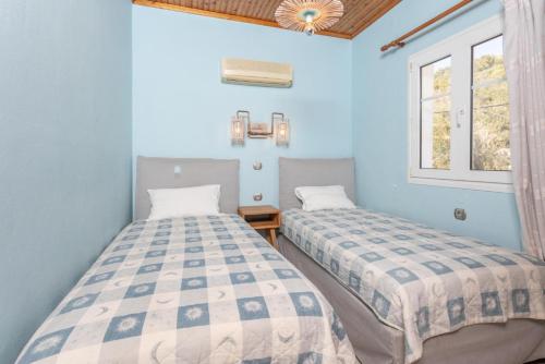 2 camas en una habitación con paredes y ventanas azules en Apartment Limani en Longos