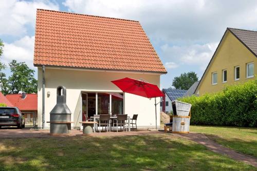 a house with a red umbrella and a table and chairs at Ferienhaus Fernweh in Göhren-Lebbin