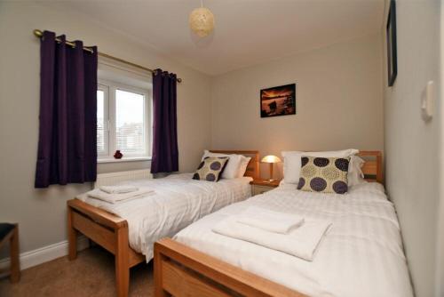1 dormitorio con 2 camas y ventana en Schooner Court No1, en Alnmouth